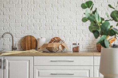 Basket with loaves of fresh bread on counter in kitchen