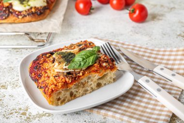 Plate with piece of tasty Italian pie and cutlery on light table
