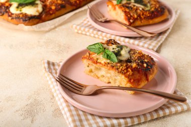 Plates of tasty Italian pie with mozzarella and pesto sauce on light table
