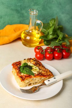 Plate of delicious Italian pie with mozzarella and pesto sauce on table