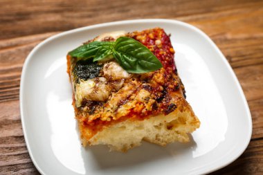Plate with tasty Italian pie with mozzarella and pesto sauce on wooden background, closeup