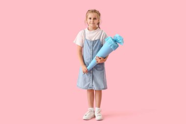 Cute little girl with blue school cone on pink background