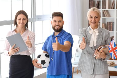 Teachers showing thumbs-up in school office