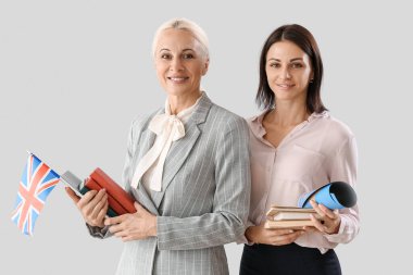 Female teachers with UK flag and books on light background