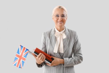 Mature English teacher with UK flag and books on light background