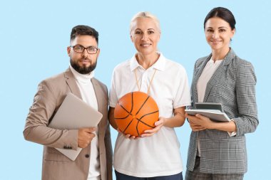Teachers with laptop, ball and books on blue background