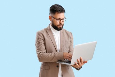 Handsome teacher of computer sciences using laptop on blue background