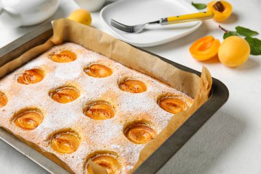 Baking tray with tasty apricot pie on table, closeup