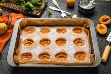 Baking tray with tasty apricot pie on dark background, closeup
