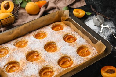 Baking tray with tasty apricot pie on dark table, closeup