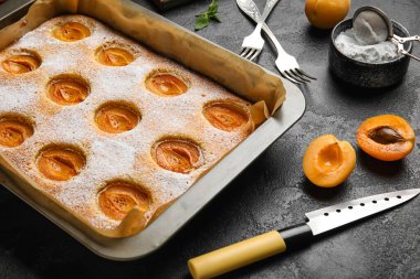 Baking tray with tasty apricot pie on dark background, closeup