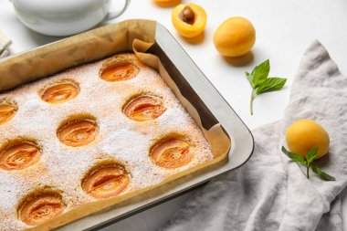 Baking tray with tasty apricot pie on light table, closeup