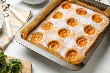 Baking tray with tasty apricot pie on light table, closeup