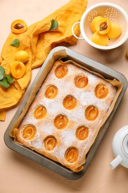 Baking tray with tasty apricot pie and fresh fruits on color background