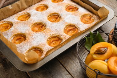 Baking tray with tasty apricot pie on wooden table, closeup