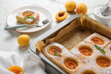 Baking tray with delicious apricot pie on light table, closeup