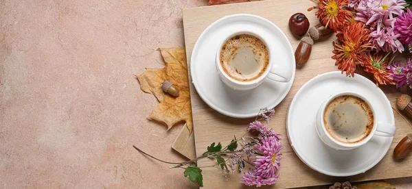 Composition with cups of coffee, flowers and autumn leaves on beige background with space for text, top view