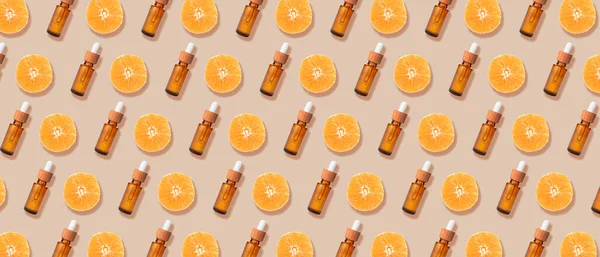 Many bottles of orange essential oil on beige background. Pattern for design
