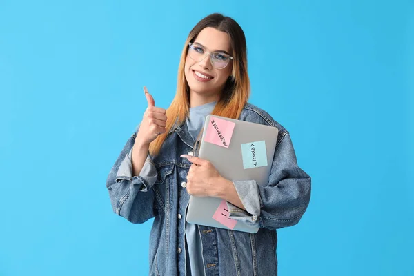 Transgender programmer with laptop showing thumb-up on blue background