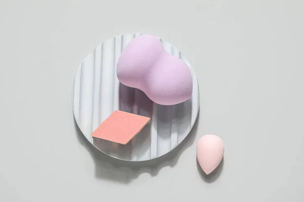 Stand with makeup sponges on grey background