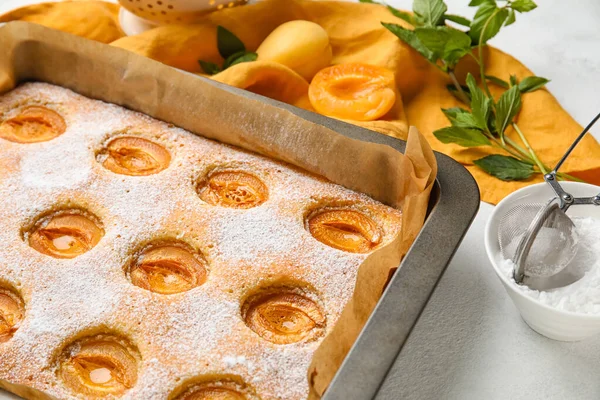 Baking tray with tasty apricot pie on table, closeup