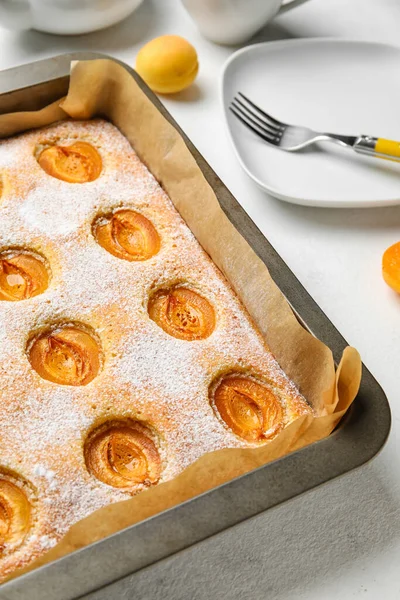 Baking tray with tasty apricot pie on table, closeup
