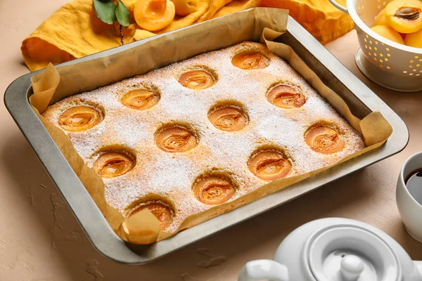 Baking tray with tasty apricot pie on color table, closeup