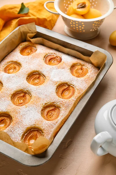 Baking tray with tasty apricot pie on color table, closeup