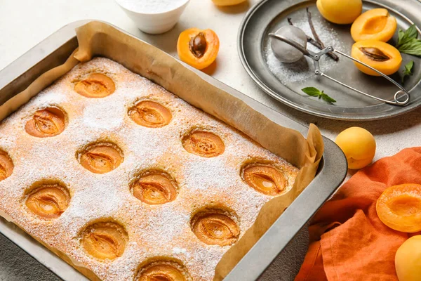 Baking tray with tasty apricot pie on table, closeup