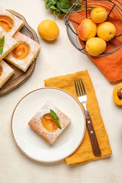 Plate with piece of tasty apricot pie on light background
