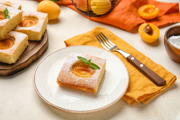 Plate with piece of tasty apricot pie on light background