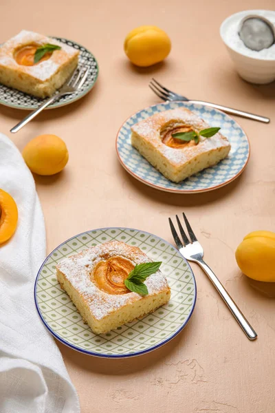 Plates with pieces of delicious apricot pie on color background