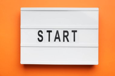 Board with word START on orange background