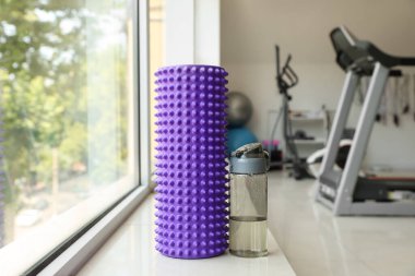 Foam roller with bottle of water on windowsill in gym