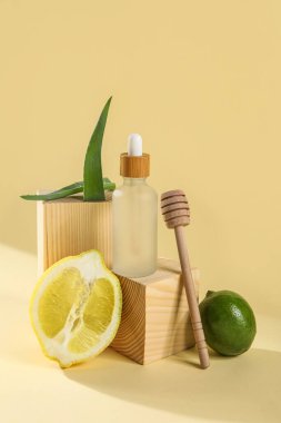 Composition with bottle of essential oil, lemon, lime and aloe leaves on color background