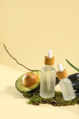 Composition with bottles of essential oil, avocado and moss on color background