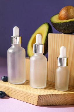 Bottles of essential oil and wooden decor on color background, closeup