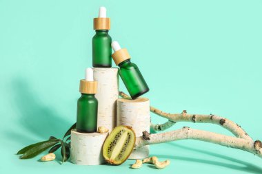 Composition with bottles of essential oil, kiwi and wooden stands on color background