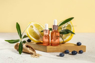 Composition with bottles of essential oil, blueberry, oatmeal and lemon on table