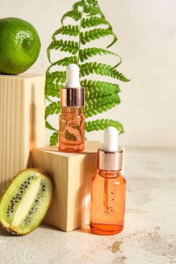 Composition with bottles of essential oil, fern leaf and wooden decor on light background