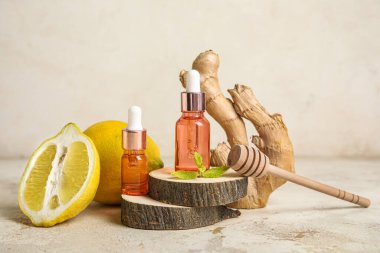Composition with bottles of essential oil, lemon and ginger root on light background