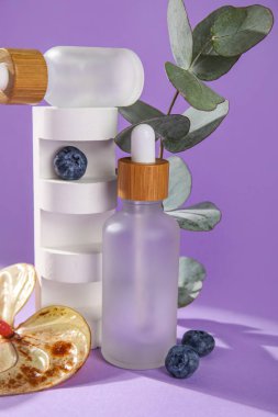 Bottles of essential oil and plaster decor on lilac background, closeup