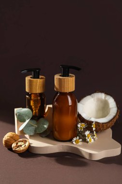 Composition with bottles of cosmetic products and natural ingredients on dark background