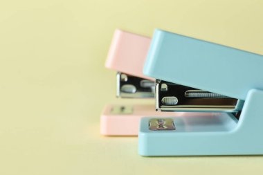 Office staplers on color background, closeup