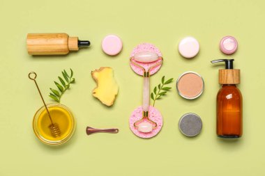 Facial massage tool with cosmetic dropper bottles, sponges and components on green background