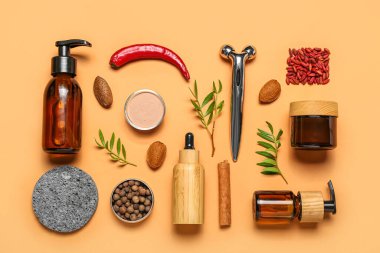 Facial massage tool with cosmetic products and natural components on beige background