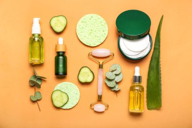 Facial massage tool with cosmetic dropper bottles, sponges and components on beige background