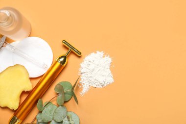 Facial massage tool with cosmetic dropper bottle, cotton pads and components on beige background