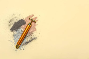 Facial massage tool with cosmetic clay on beige background