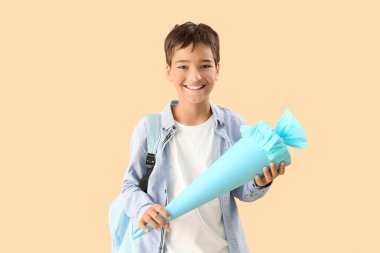 Little boy with blue school cone on beige background